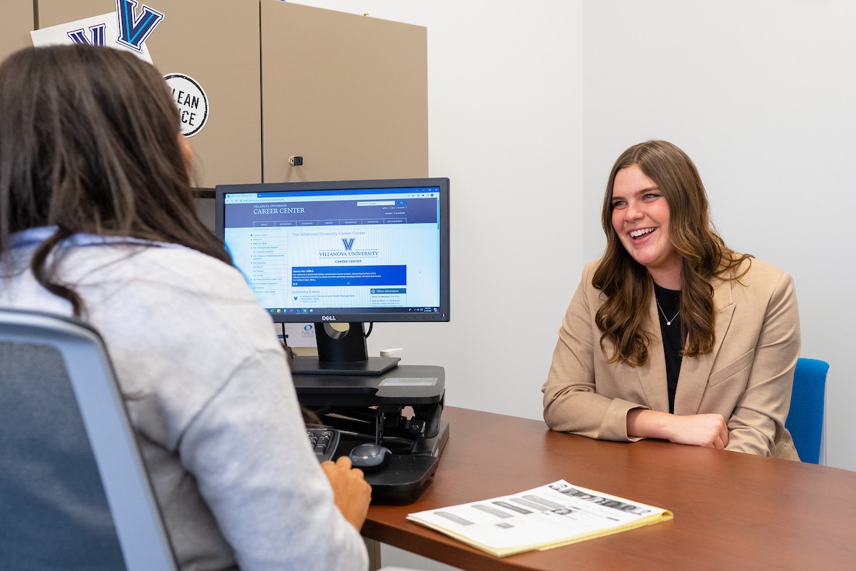 Student sitting behind a desk talking with a Career Center employee.