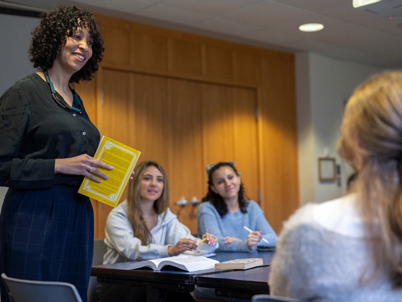 Associate Professor of English Adrienne Perry, PhD, leads a discussion with students sitting at a table.