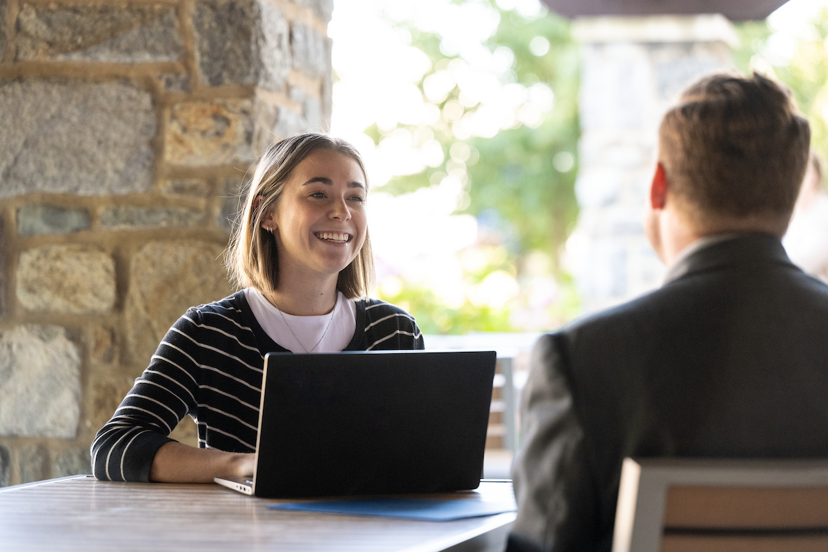woman with a laptop sitting at a table outside