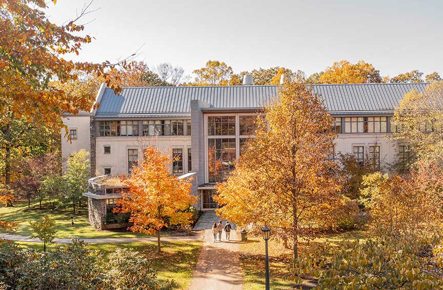 A building on the campus of Cabrini University is surrounded by vibrant fall foliage.